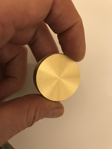 La medalla RA Psi-Generator en latón, sostenida entre dos dedos